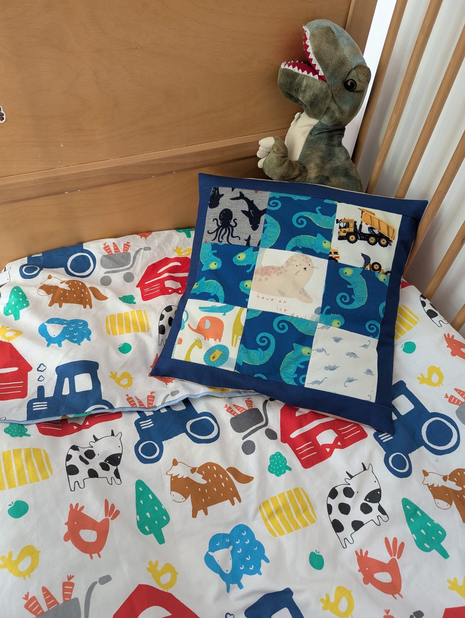 Patchwork cushion displayed on a baby cot with toys