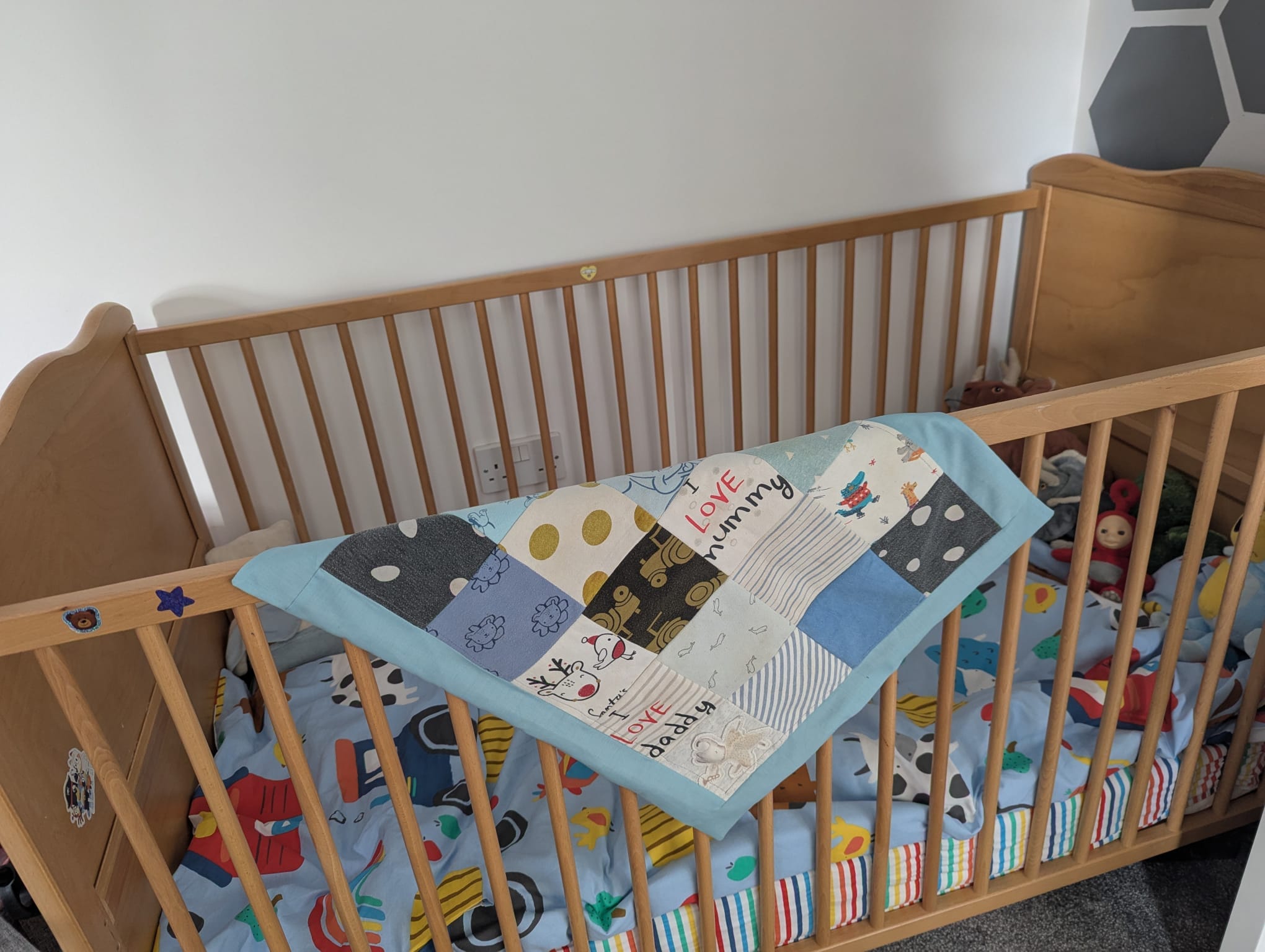 A handmade patchwork blanket draped over a wooden cot